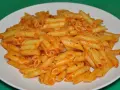 Macarrones penne con salsa de tomate y hierbas en un plato blanco.