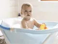 Urocze dziecko w niebieskiej wanience z żółtą kaczką. Kąpiel w wanience jest świetną zabawą, a dziecko może w niej przebywać, dopóki nie zacznie samodzielnie siadać i wstawać.