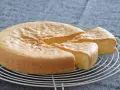 Bizcocho sin gluten esponjoso y dorado, recién cortado en porciones sobre una rejilla.