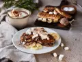 En härlig nutella macka med banan och marshmallows, toppad med grädde och kakao. Bredvid står en kopp varm choklad.
