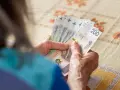 Dłonie starszej osoby liczą banknoty 200 zł. Może to być związane z drugą waloryzacją emerytur, która poprawia byt seniorów.