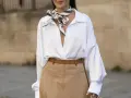 Elegancka biała koszula i beżowa spódnica to świetne **stylizacje jak ukryć brzuch**. Wzorzysty szalik dodaje szyku.