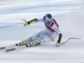 Lindsey Vonn w pełnym pędzie, w białym kombinezonie z napisem USA, na nartach HEAD. Widoczny moment tuż przed upadkiem.