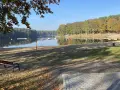 Spokojne jezioro z pomostami i sprzętem wodnym, otoczone jesiennym lasem. Idealne miejsce na odpoczynek po przejażdżce po trasach rowerowych Szczecin.