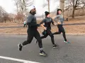 Tre amici corrono in un parco in inverno, mostrando come vestirsi per correre in questa stagione con abbigliamento tecnico.