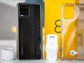 Zestaw z telefonem realme 8: czarny smartfon, ładowarka, kabel i przezroczyste etui.