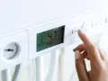 Dito, la mano preme il pulsante "MOD" su una caldaia. Il display mostra 47°C, ma la pressione acqua calda è bassa.