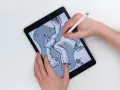 Ręce tworzą rysunek na iPadzie, używając Apple Pencil. Stylizowane postacie unoszą się w abstrakcyjnym tle.