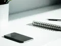 A smartphone, notebook, and pen sit on a desk, ready for a startup auditor's analysis.