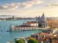 Venice cityscape with canals, boats, and historic buildings under a sunny sky.