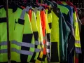 Rzędy jaskrawożółtych i pomarańczowych kurtek roboczych z odblaskowymi pasami. Zastanawiasz się, ubrania robocze co ile przysługują?