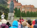 Grupa turystów słucha przewodnika przy pomniku Kopernika. To jedna z wielu atrakcji Warmii, gdzie historia ożywa.