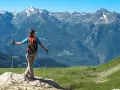 Donna con zaino e bastoncini da trekking ammira i maestosi **sentieri Valle d'Aosta** e le cime innevate.