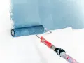 Rouleau à peinture bleu appliquant une bande de couleur sur un mur blanc. L'outil est prêt pour peindre.