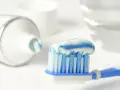 Szczoteczka z pastą, zawierającą aminofluorek i fluor, gotowa do mycia zębów.