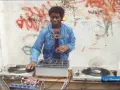 DJ Kool Herc, der oft als derjenige gilt, der Hip Hop erfunden hat, legt auf. Graffiti zieren die Wand im Hintergrund.