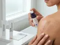 Kobieta aplikuje żel na bliznę. Na blacie widać różne rodzaje allantoinu i cepalinu, a także ulotkę.