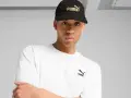 Mężczyzna w czarnej czapce z logo Puma i białej koszulce.