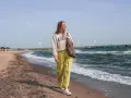 Frau spaziert am stein strand entlang, die Wellen rauschen.