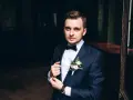 Elegancki mężczyzna w granatowym smokingu z kamizelką, z butonierką.