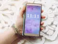 Dłoń trzyma telefon z wyświetloną godziną 11:11, co może mieć szczególne znaczenie.