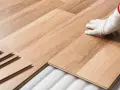 Instalación de suelo laminado. Mano con guante blanco colocando una tabla. Consulta el precio colocacion suelo laminado.