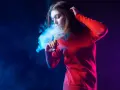 Joven exhala humo azul de un vaper. El vaper con nicotina es malo para la salud.