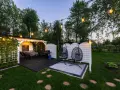Idealne miejsce na camping w Ochabach: zadaszony taras z grillem, stolikiem i wiszącymi fotelami. Wieczorem rozświetla go girlanda żarówek.
