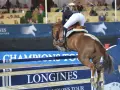 Un cavalier pro et son cheval brun franchissent un obstacle lors d'une compétition d'équitation.