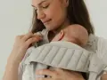 Mutter hält ihr Neugeborenes in einer Trage. Die warme Kleidung neugeborene winter schützt das Baby vor Kälte.