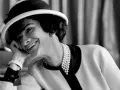 Coco Chanel sorride con un cappello e perle, un'icona di stile che sembra raccontare la storia di quando è nata Coco Chanel.