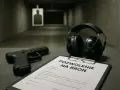 Pistolet, słuchawki i formularz "Pozwolenie na broń" na strzelnicy.