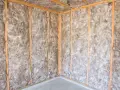 Coin d'une pièce en construction, murs et plafond recouverts d'une isolation ouate de cellulose.