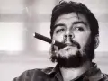 Portrait en noir et blanc de Che Guevara, cigare aux lèvres, regard intense. L'image évoque sa légende, même après sa mort.