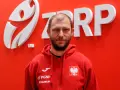 Marcin Wichary, w czerwonej bluzie z orłem, przed logo ZRP.