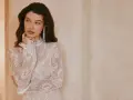 Elegancka, biała sukienka bez dekoltu, zdobiona koronką i cekinami, z długimi rękawami.
