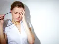 Kobieta z bólem głowy, trzymająca okulary. Może szukać ulgi, jak po pregabalin.