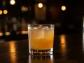En iskall, gyllene drink med en stor isbit i ett glas på en mörk träyta. En perfekt spicy margarita för en kväll ute.