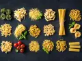 Różnorodne włoskie dania z makaronem: od tagliatelle i spaghetti po farfalle i penne, z dodatkiem pomidorków i bazylii.