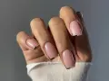 Mano con unghie quadrate naturali, smalto rosa tenue e un sottile dettaglio grafico nero sulla punta.