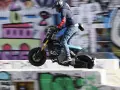 Młody mężczyzna na elektrycznym motocyklu BMW CE02 wykonuje skok na tle kolorowego graffiti.