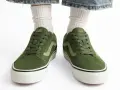 Zielone trampki Vans z jasną falą. Czy to rozmiar buta 11.5 cm? Białe skarpetki i podarte jeansy dopełniają stylizację.