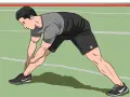 Man stretching his legs on a green indoor track, preparing for an intense indoor sprint workout.