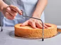 Hände schneiden mit einem Tortenbodenschneider einen Biskuitboden für ein einfaches Cassata Rezept.