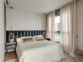 Acogedora habitación pequeña con cama grande, cabecero tapizado, mesitas de noche modernas y cortinas elegantes.