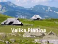 Tradycyjne drewniane domki pasterskie na zielonych wzgórzach Velika Planina w Słowenii, z majestatycznymi górami w tle.