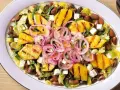 Ensalada de frijoles, piña a la parrilla, queso y cebolla morada en un plato blanco.