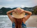 Frauenhände halten Hut am Strand. Endlich Zeit für Urlaub, der gesetzliche Urlaubsanspruch ab 50 ist wohlverdient.