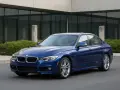 Niebieskie BMW F30 na tle nowoczesnego budynku. Zastanawiasz się nad jego **koszty utrzymania**?