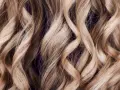 Falujące, blond włosy z subtelnymi refleksami, które mienią się w świetle, tworząc efekt głębi.